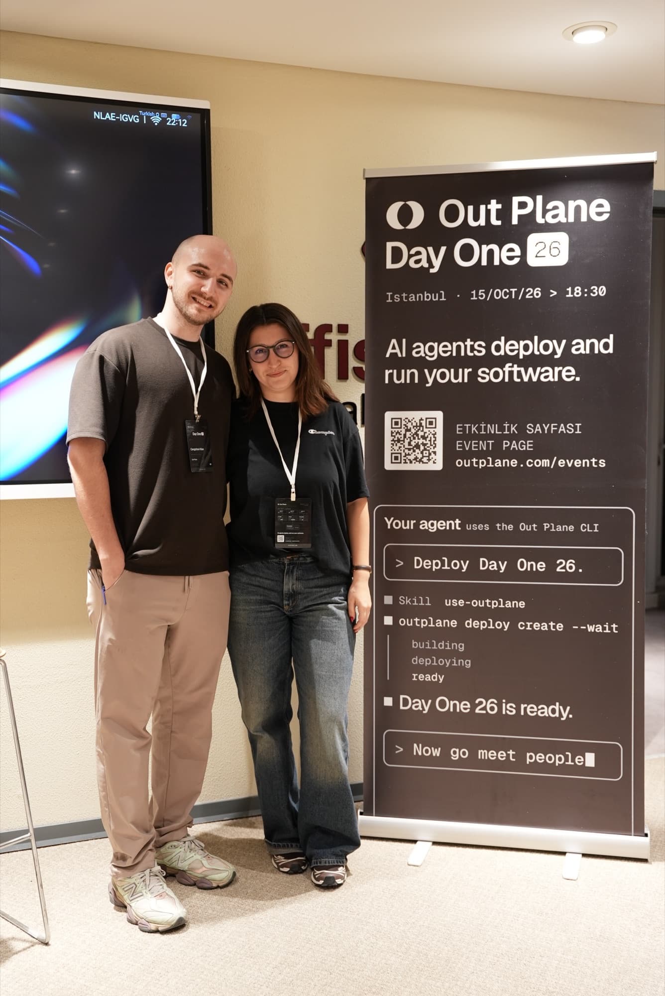 Two attendees next to the Day One roll-up banner